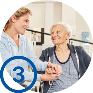 Nr. 3 - Entlastung: Eine Frau hält die Hand einer Seniorin im Rollstuhl. Beide lächeln sich an.