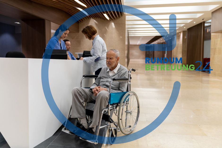 Älterer Mann im Rollstuhl steht vor einem Tresen im Krankenhaus im Hintergrund Frauen im Gespräch zum Thema Entlassmangement: Betreuung zuhause