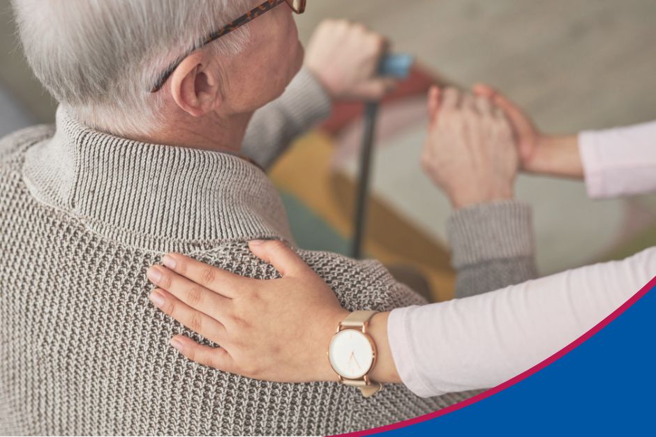 Nahaufnahme von hinten. Frau legt fürsorglich die Hand auf den Rücken eines alten Mannes zum Thema Rundumbetreuung24 Leistungen