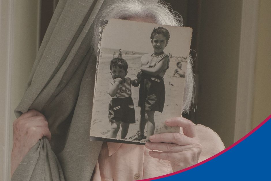 Ältere Frau hält sich ein Bild von ihrem jüngeren Ich vor das Gesicht zum Thema Demenzberatung