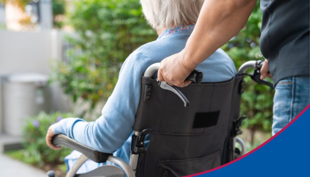 Seniorin im Rollstuhl wird von einem Mann geschoben.