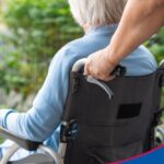 Seniorin im Rollstuhl wird von einem Mann geschoben.